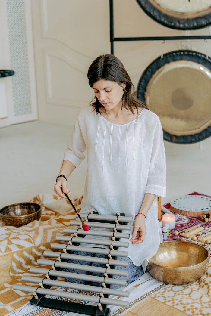 Woman playing xylophone in serene indoor environment, creating tranquil music.