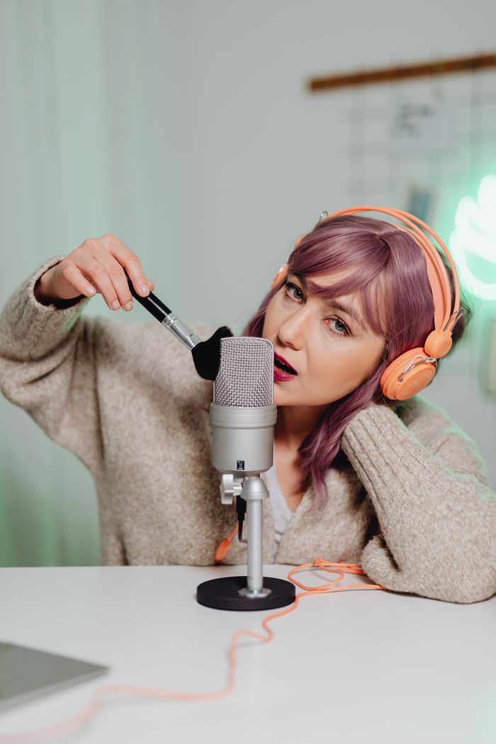 About Woman in cozy setup using brush and microphone for ASMR recording at home.